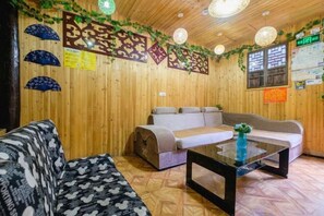 Una habitación con paredes de madera, un sofá, un sillón y una mesa de centro de vidrio.