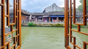 A traditional wooden structure with a river in the foreground. - Aunty Ji Inn (Tongxiang)