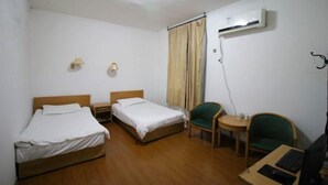 A hotel room with two single beds, a desk with a computer, a chair, an air conditioning unit, and a small table with a lamp. - OYO Quzhou Zhenxing Hotel (Quzhou)