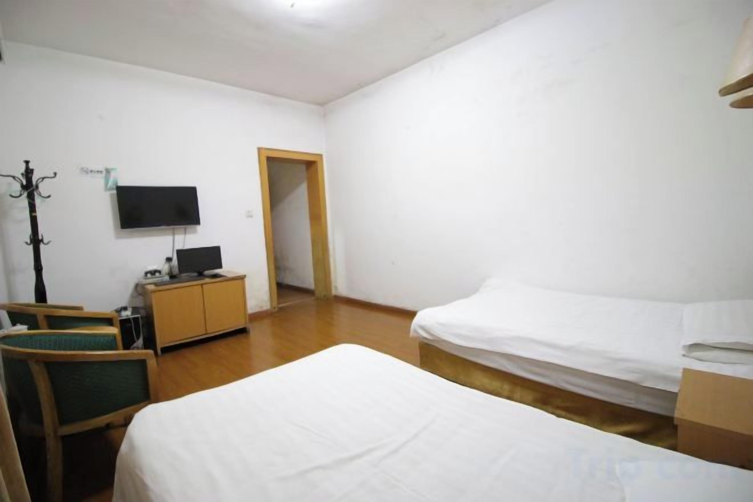 A hotel room with a bed, a desk, a chair, a television, and a wardrobe.