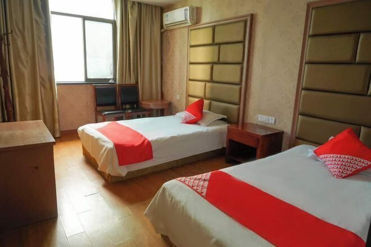 A hotel room with two beds, a desk, and a chair.