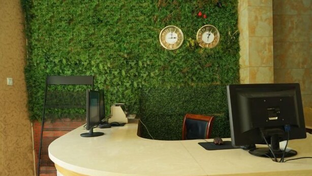 A reception desk with two clocks on the wall, a computer monitor, and a telephone. - OYO Quzhou Zhenxing Hotel (Quzhou)