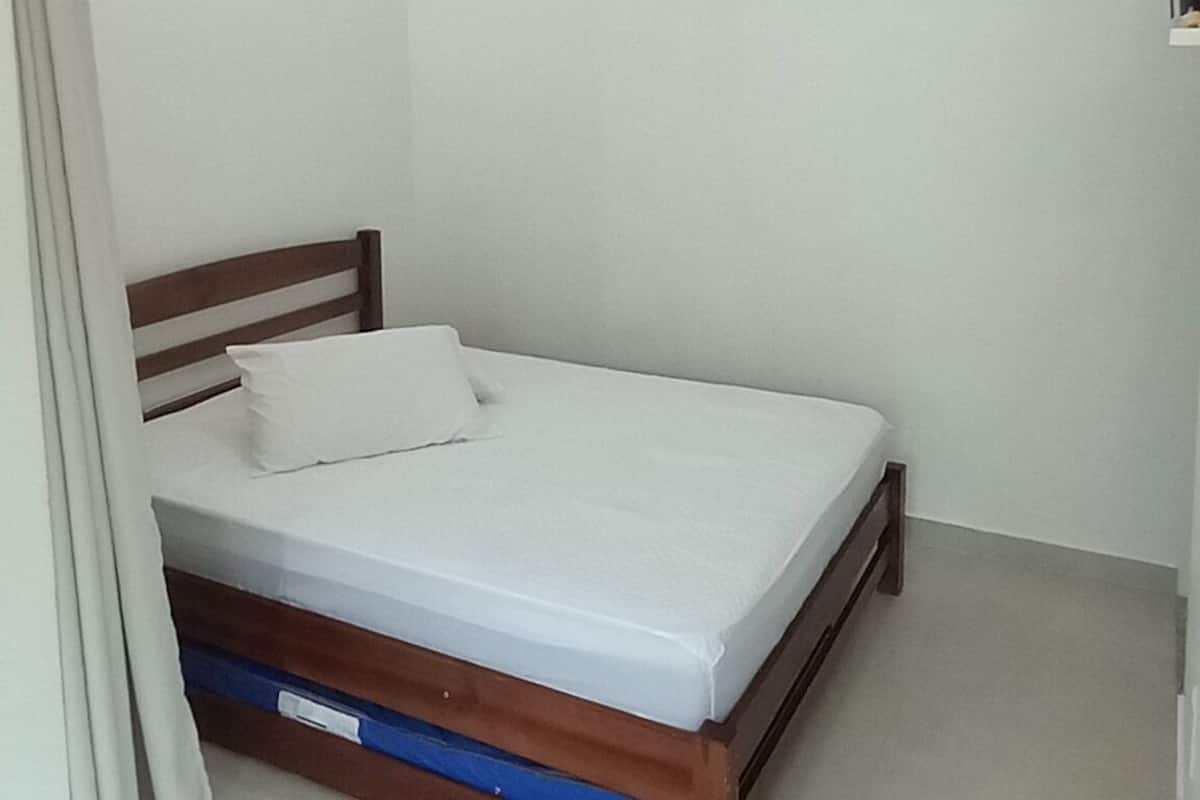 A bedroom with a single bed, white walls, and a ceiling light.