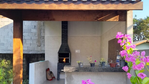 Eine Terrassenanlage im Freien mit eingebautem Kamin, Betonboden und Pflanzen in Töpfen.
