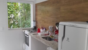 Eine moderne Küche mit weißen Schränken, einer Granit Arbeitsplatte, einem Einbauofen, einer Spüle und einem Kühlschrank.