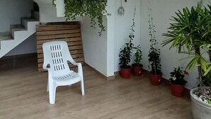 Ein modernes Interieur mit einem weißen Sessel, einer Treppe und mehreren Kübelpflanzen.
