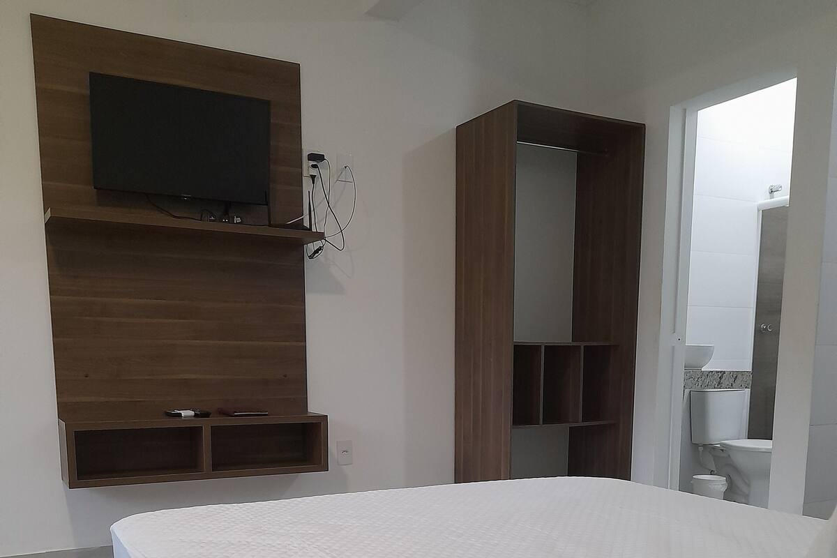 A bedroom with a bed, a TV mounted on the wall, and a wardrobe.
