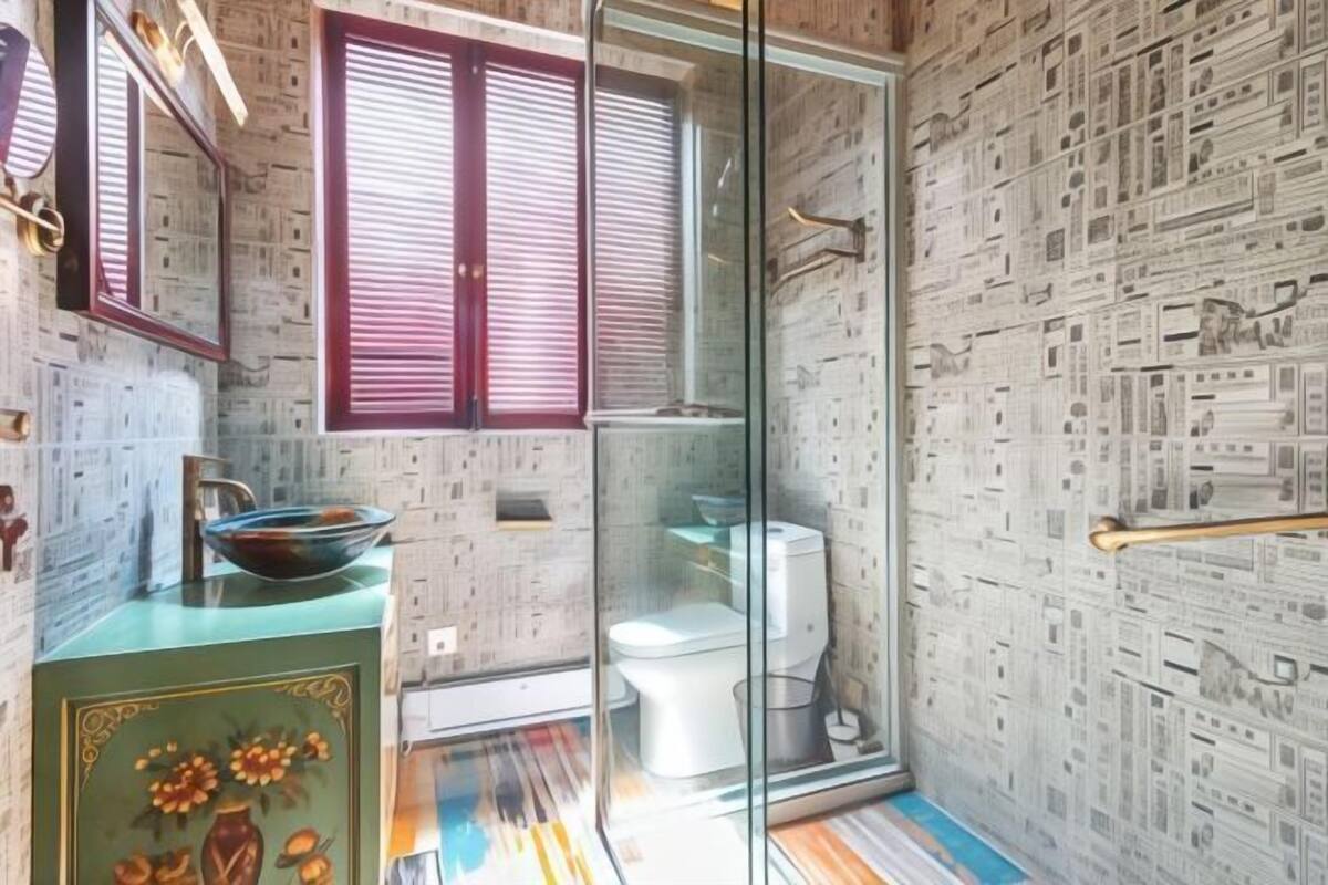 Une salle de bain dotée d’une douche à parois de verre, de toilettes et d’un lavabo agrémenté d’un récipient décoratif.