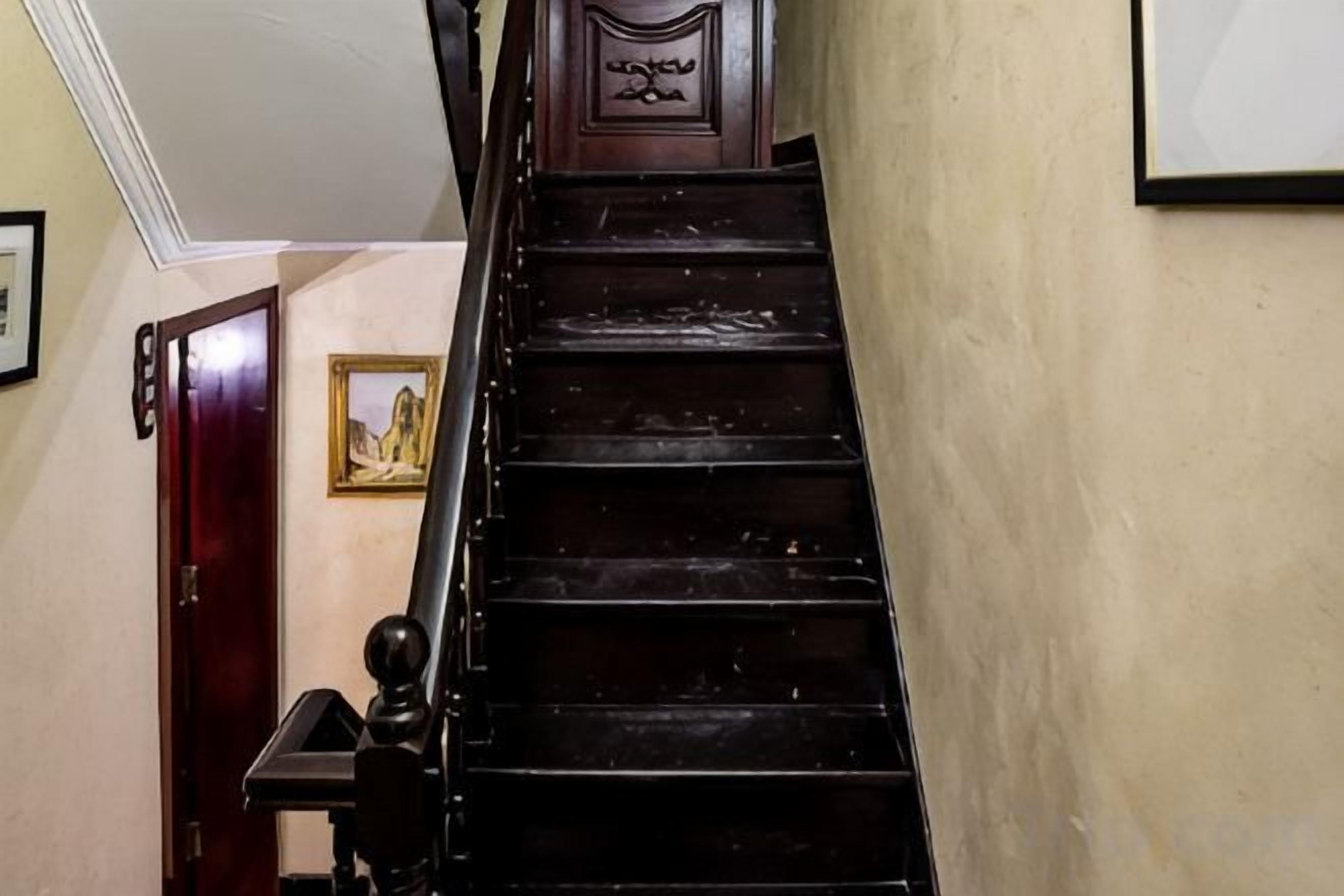 A wooden staircase with a handrail, a door at the bottom, and a framed picture on the wall.