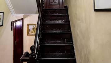 A wooden staircase with a handrail, a door at the bottom, and a framed picture on the wall.