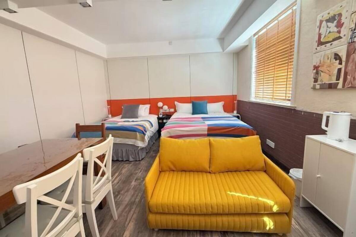 Une chambre d’hôtel de taille réduite, comprenant deux lits, un canapé, une table à manger et des chaises.