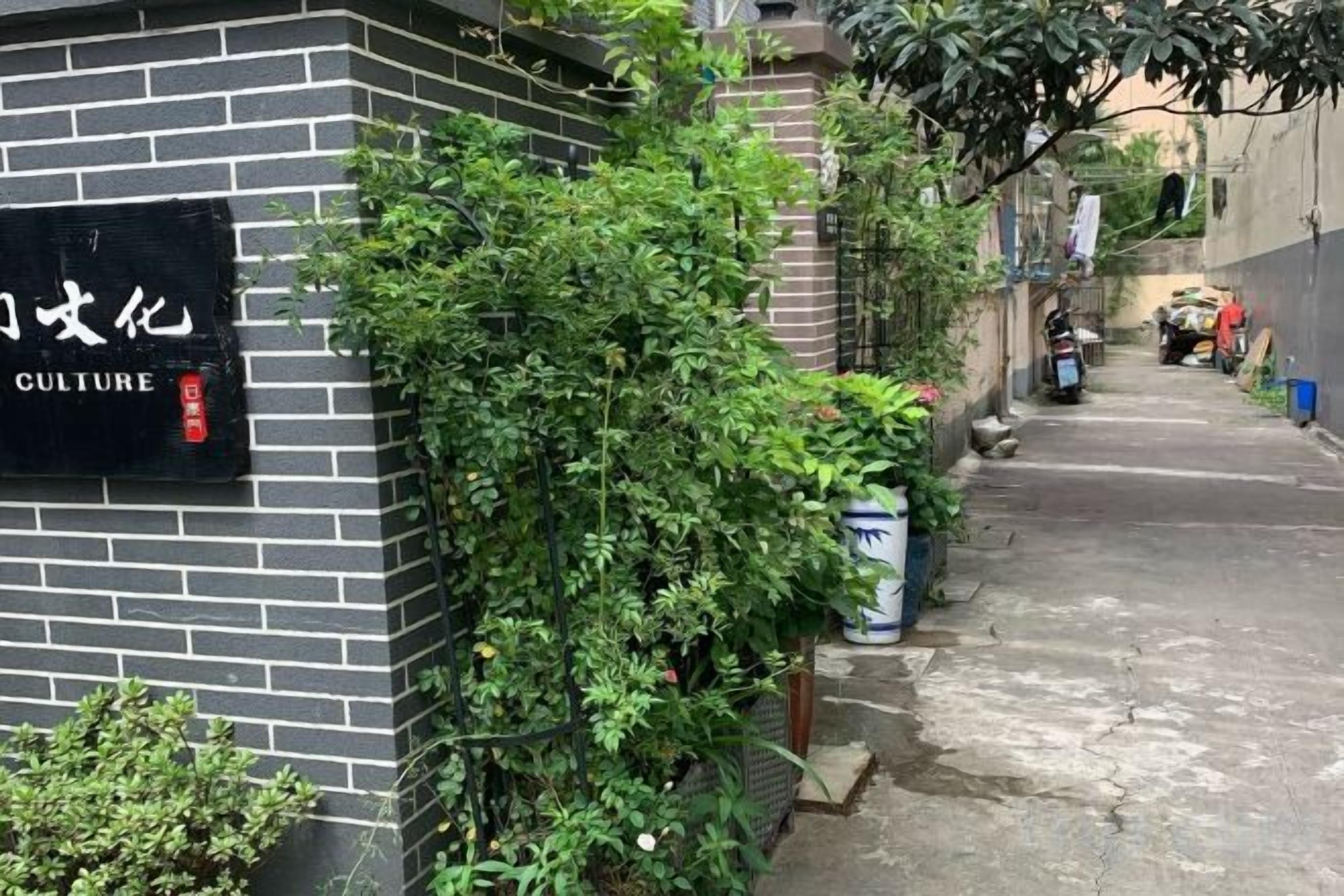 Un callejón estrecho con un muro de ladrillo a la izquierda, un cartel que dice 'CULTURE' y una moto estacionada a la derecha.