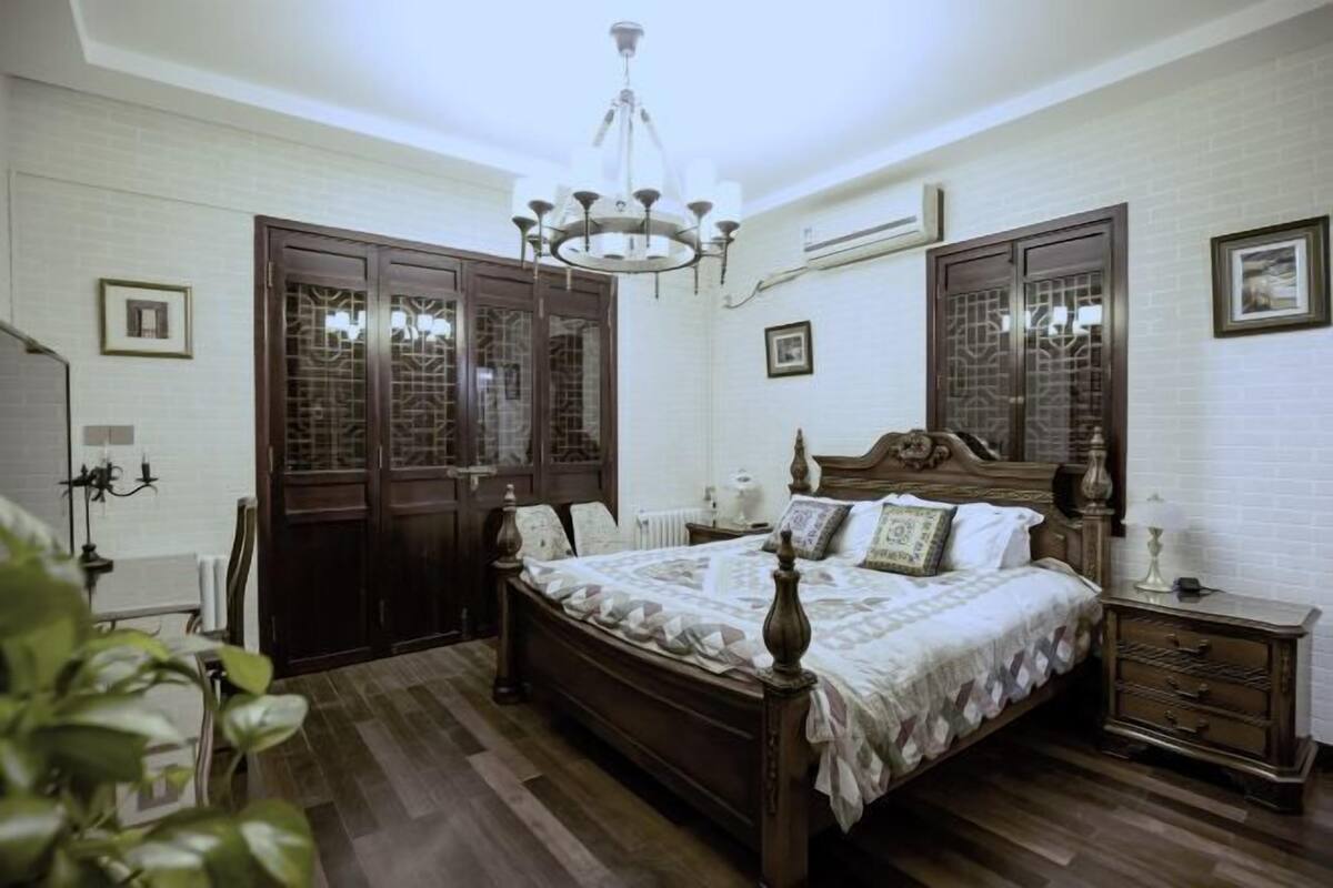 Une chambre à coucher avec un lit en bois, une table de chevet, un lustre et des portes de style traditionnel.