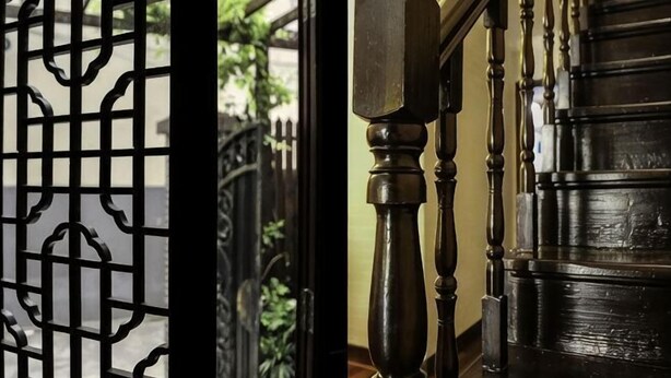 A wooden staircase with a balustrade and a black metal gate. - Shanghai Shikumen Culture Homestay (Shanghai)