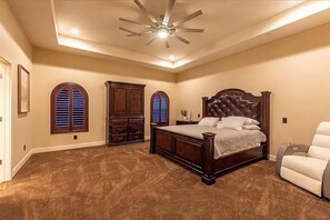 A bedroom with a large bed, a ceiling fan, and two windows with shutters. - Luxury Spacious Stay (Eagle Pass)