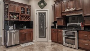 Une cuisine avec des armoires en bois, des appareils électroménagers en acier inoxydable et une guirlande décorative accrochée à la porte.