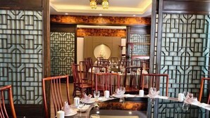 Restaurante com cadeiras e mesas de madeira, algumas com guardanapos brancos e copos.