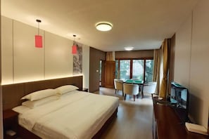 A hotel room with a bed, a desk, a chair, a television, and a window with curtains.