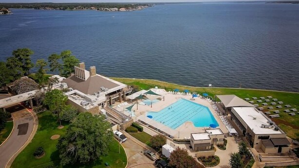 Vista aérea de un resort con una gran piscina, un estacionamiento y vistas al mar.
