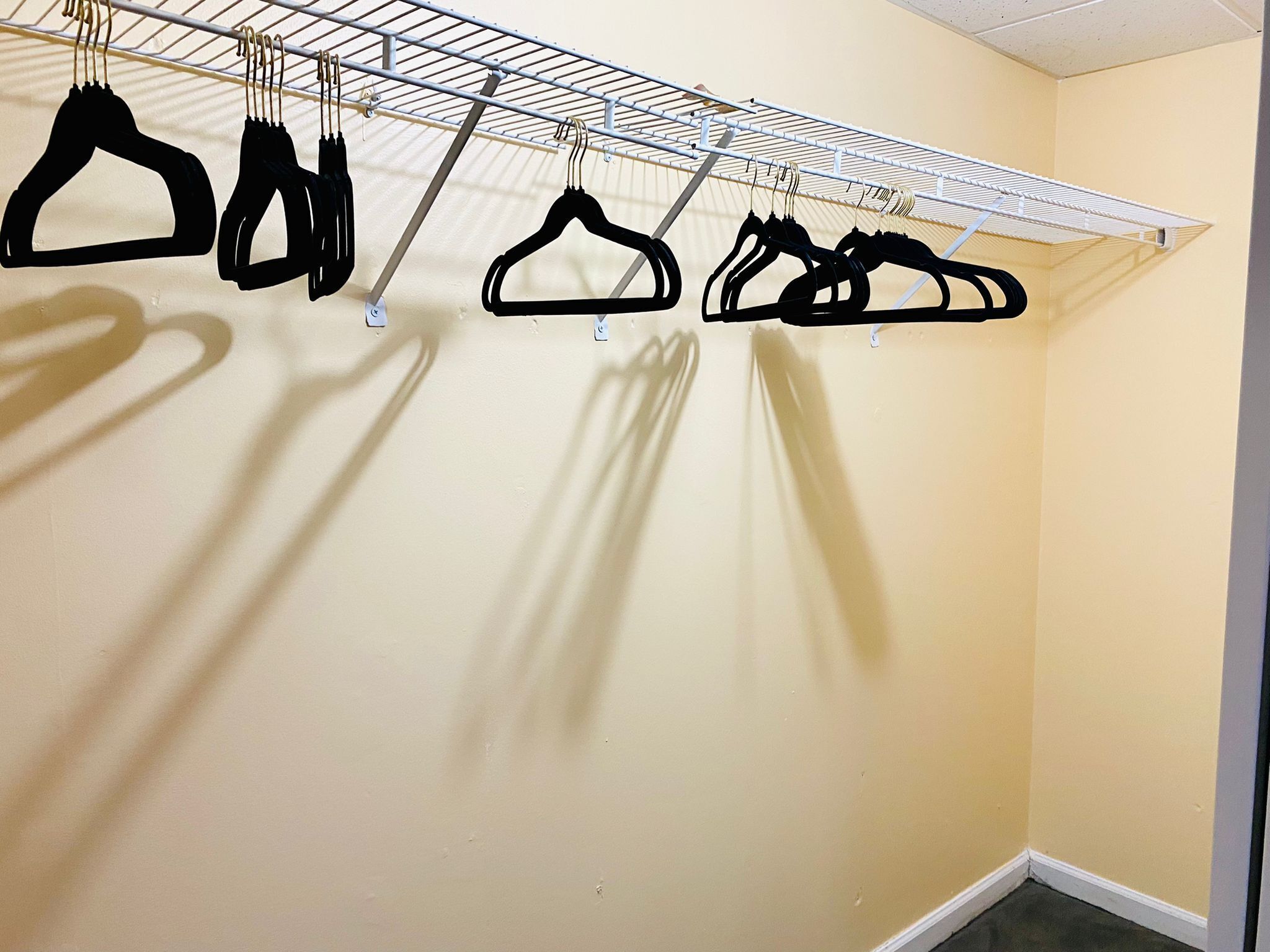 A room with a white metal drying rack against a cream-colored wall.