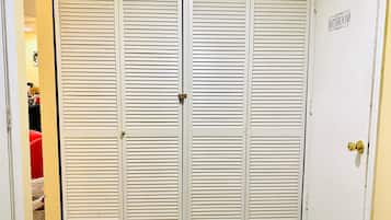 Un placard blanc fermé, doté de portes à persiennes horizontales, d’une poignée de porte en laiton et d’une pancarte indiquant « Salle de bain » sur le côté droit.