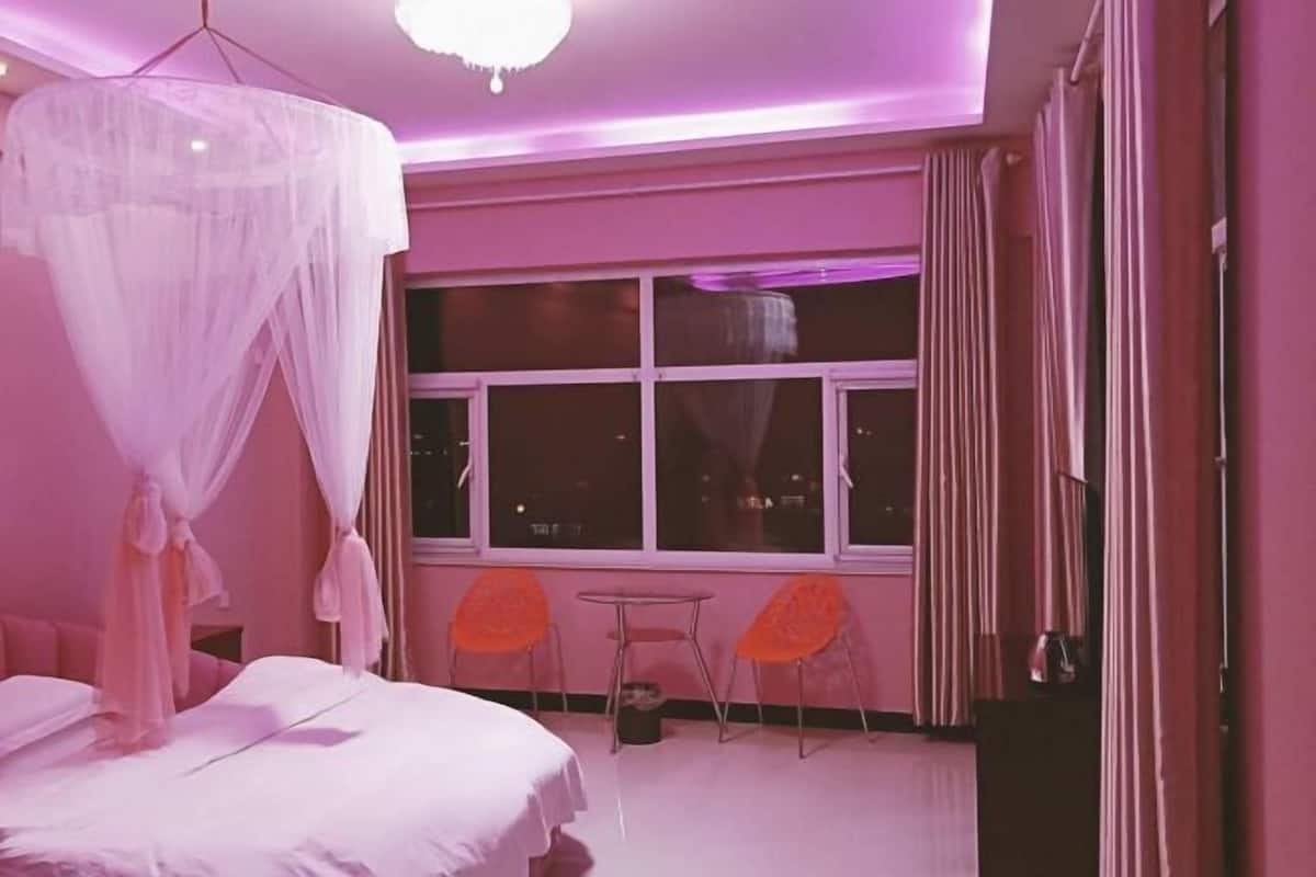 A bedroom with a bed, a window, and two chairs.