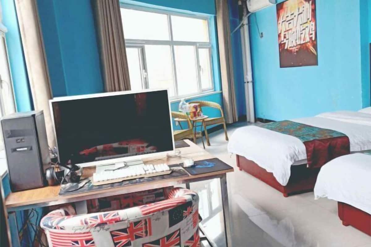A room with a bed, a desk with a computer, a chair, and a window.