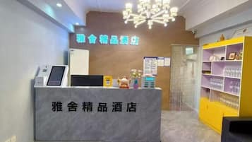 Zona de recepción de un hotel con mostrador de mármol, quiosco digital y mostrador de atención al cliente.