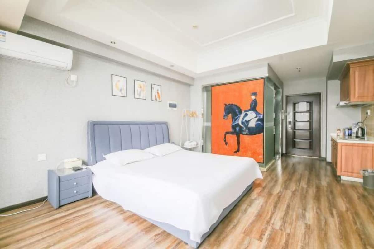 Quarto com cama, mesa de cabeceira e um quadro na parede.