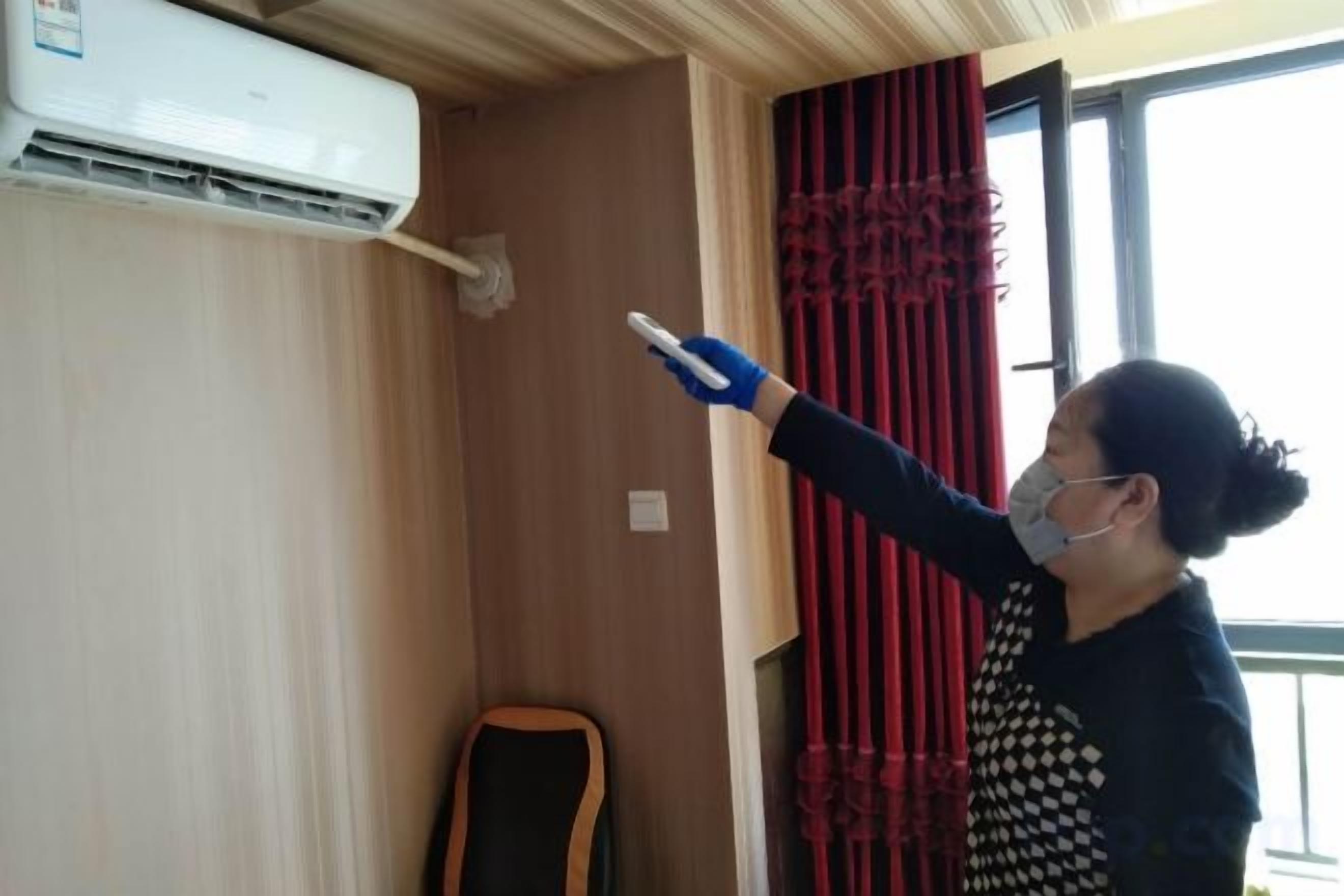 A person pointing at a wall-mounted air conditioning unit.