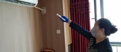 A person pointing at a wall-mounted air conditioning unit.