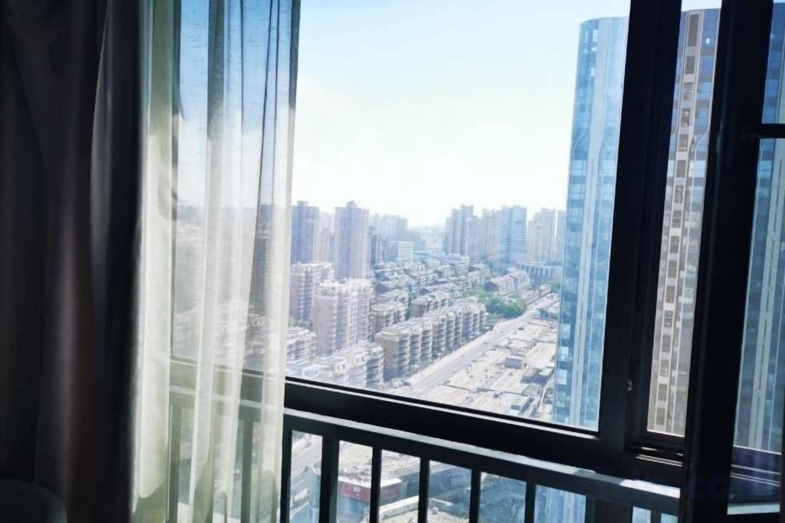 A view from a high-rise building with a clear sky, featuring tall buildings and a cityscape.