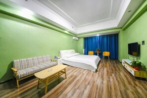 A hotel room with a bed, a sofa, a coffee table, a TV, and a desk with a chair. - Yiyi Sentiment Apartment Hotel (Bengbu)