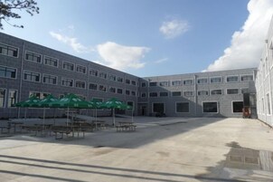 A courtyard with a building, outdoor tables, and green umbrellas.