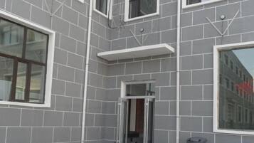 A building facade with a grey tiled exterior, multiple windows, and a door.
