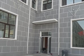 A building facade with a grey tiled exterior, multiple windows, and a door. - Wanda Motel (Bei'an)