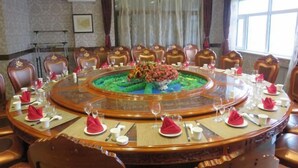 A conference room with a round table, chairs, and a floral centerpiece. - Wanda Motel (Bei'an)