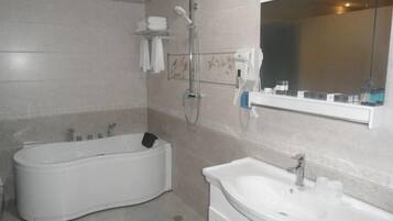 Een badkamer met een bad, wastafel, douche en spiegel.