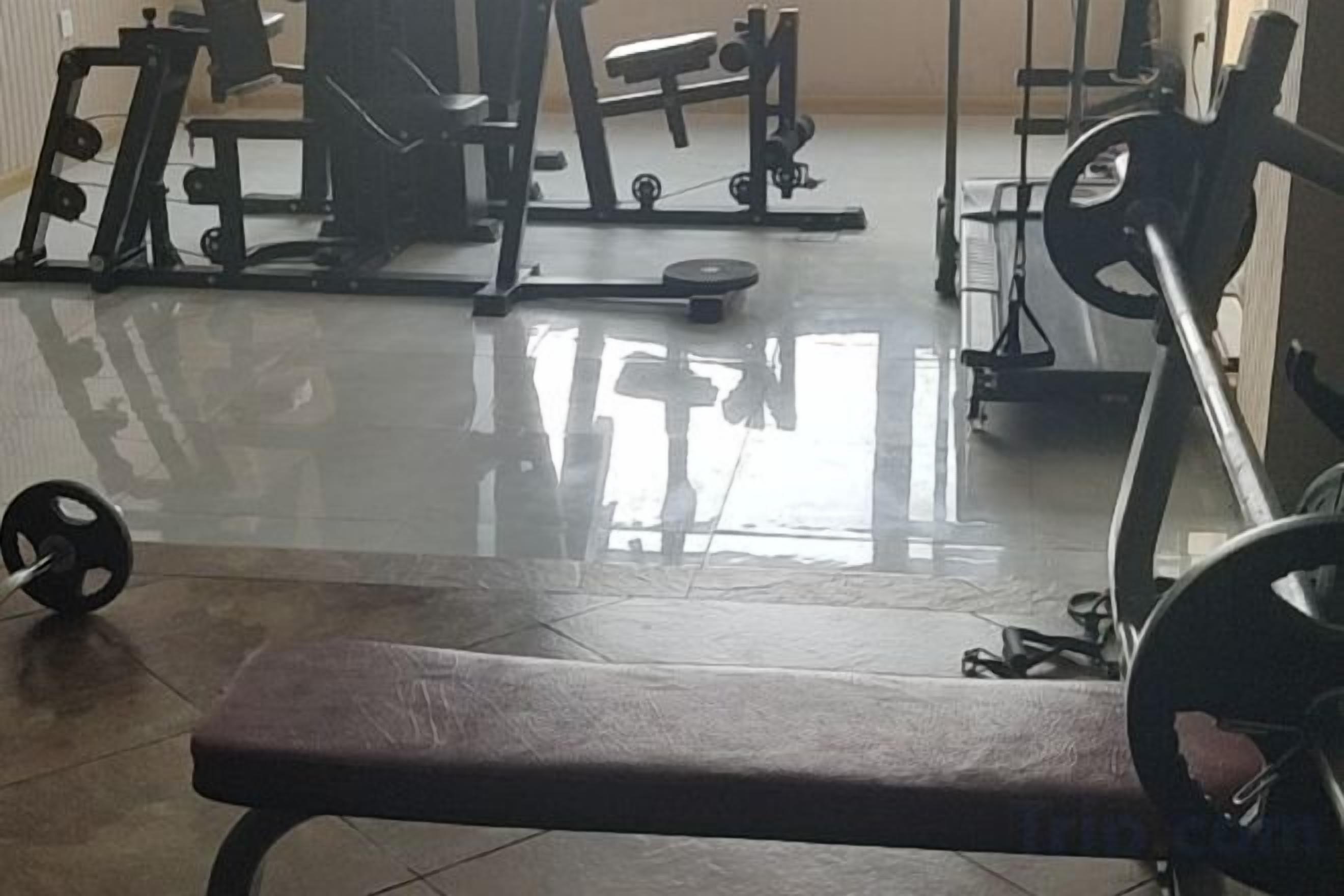 Un gimnasio con equipo de ejercicio, una banca y un soporte para pesas.