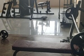 A gym with exercise equipment, a bench, and a weight rack. - Wanda Motel (Bei'an)