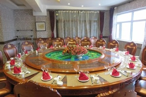 A conference room with a round table, chairs, and a floral centerpiece. - Wanda Motel (Bei'an)