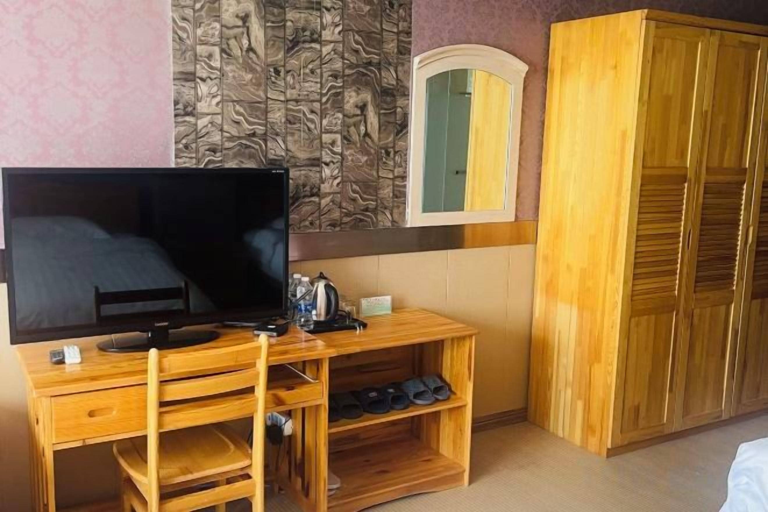 Ein Zimmer mit einem Holz-Fernsehschrank, einem Flachbildfernseher, einem Holzschrank und einem Spiegel.
