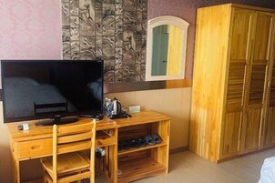 Una habitación con un mueble bajo de madera para el televisor, un televisor de pantalla plana, un armario de madera y un espejo.