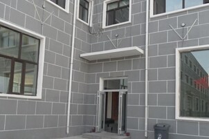 Un edificio con fachada de tejas grises, varias ventanas y una puerta con paneles de vidrio.