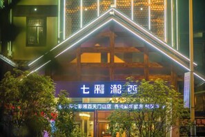A hotel with a prominent entrance, a signboard with text, and a well-lit facade. - Colorful Xiangxi Inn (Zhangjiajie)