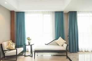A modern hotel room with a sofa, a small side table, and a vase of flowers. - Colorful Xiangxi Inn (Zhangjiajie)