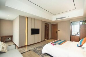 A modern hotel room with a large bed, a flat-screen TV, a wooden wardrobe, and a small bedside table. - Colorful Xiangxi Inn (Zhangjiajie)