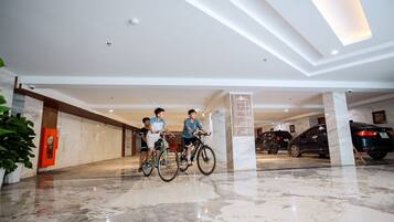 A spacious lobby with a marble floor, a reception desk, and a parking area with cars.