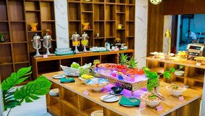 A buffet setup with various food items and a decorative plant. - The King Hotel condotel Thai Nguyen (Phan Dinh Phung)