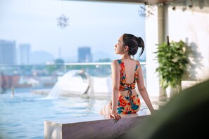 A person sitting by a pool with a cityscape in the background. - The King Hotel condotel Thai Nguyen (Phan Dinh Phung)